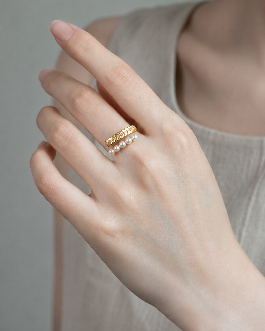 Close-up of the Pearl Laurel Open Ring styled on hand with simulated pearls and a laurel-inspired design.