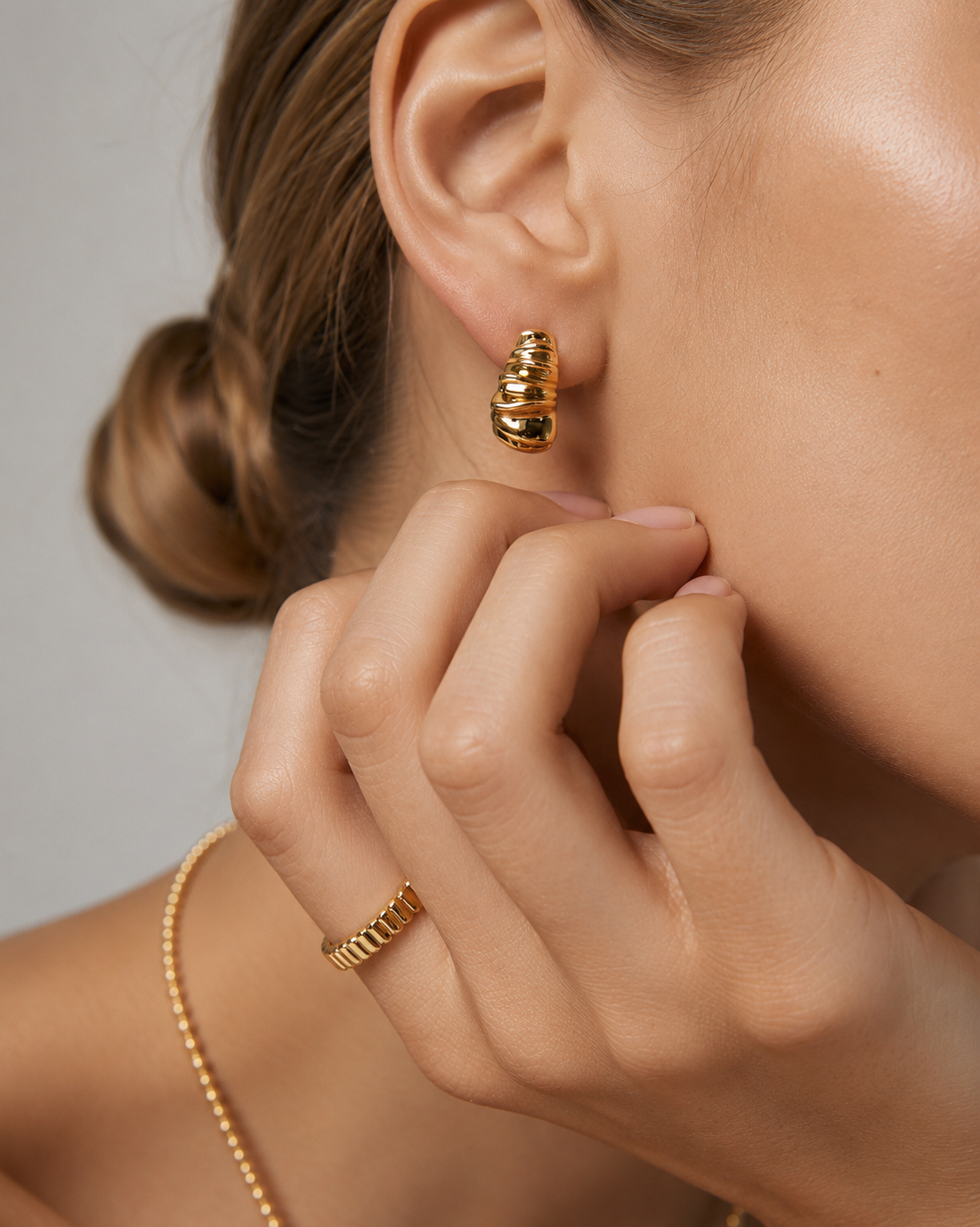 Close-up of gold Ripple Huggie Earrings paired with a matching textured ring in a minimalist everyday look.