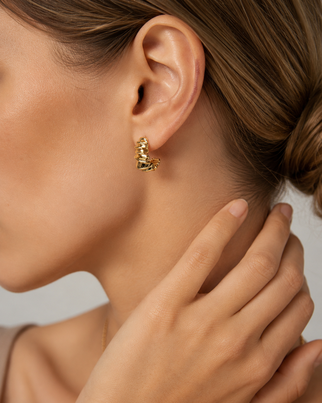 Model wearing gold Ripple Huggie Earrings with a modern sculptural silhouette for everyday styling.