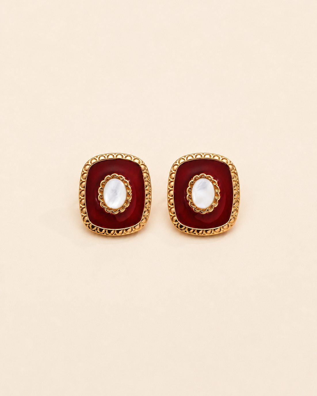 Vintage-inspired red enamel stud earrings with natural shell center and gold-tone detailing, square silhouette on a cream background.