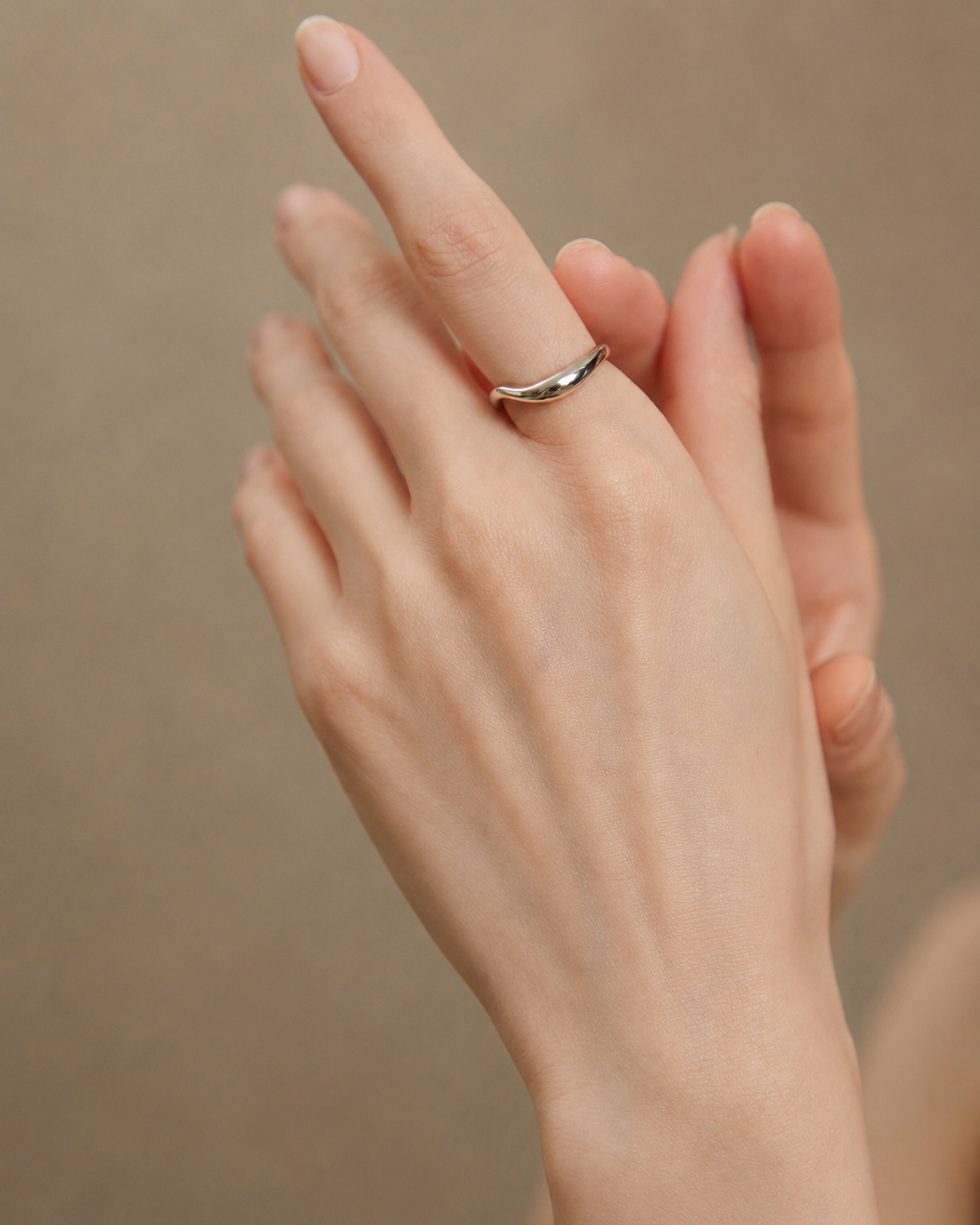 Model wearing the Sculpt Wave adjustable ring in S925 sterling silver with thick 18K white gold plating, showcasing a minimalist organic curved design.