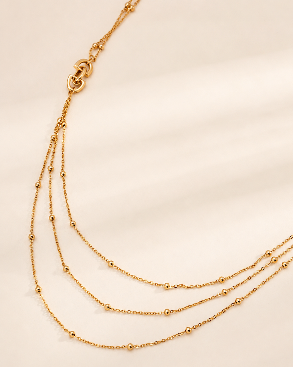 Gold layered bead necklace with three dainty chains, lightweight design and adjustable extender chain.