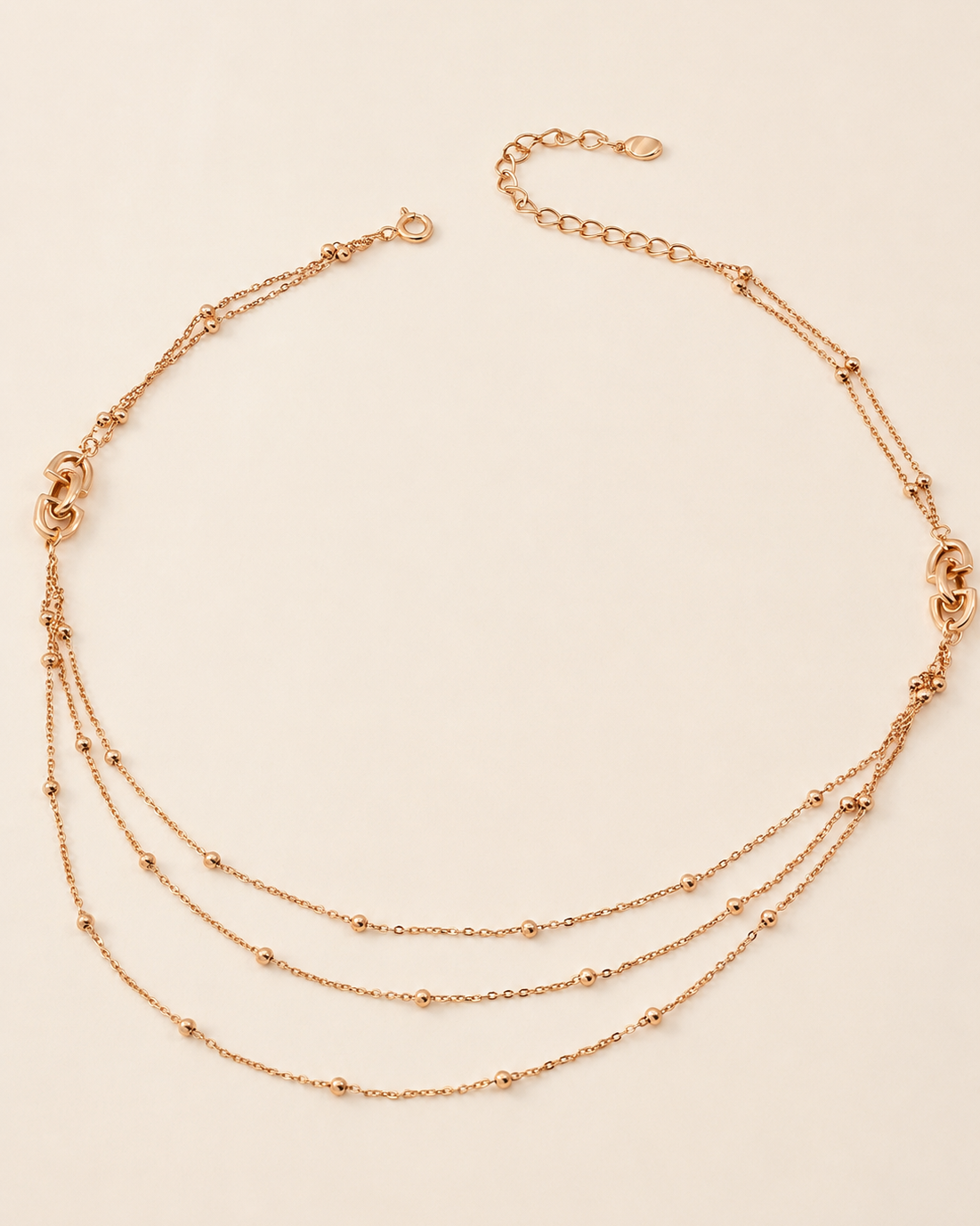 Starlit Layers Necklace featuring three delicate gold chains with polished bead accents and adjustable length.