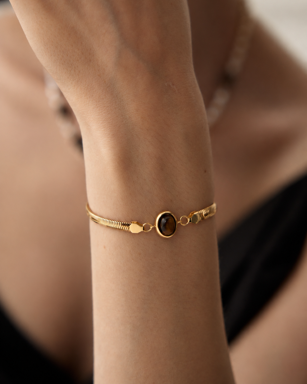 Close-up of a woman wearing a Tiger Eye herringbone bracelet in thick 18K gold plated S925 sterling silver.