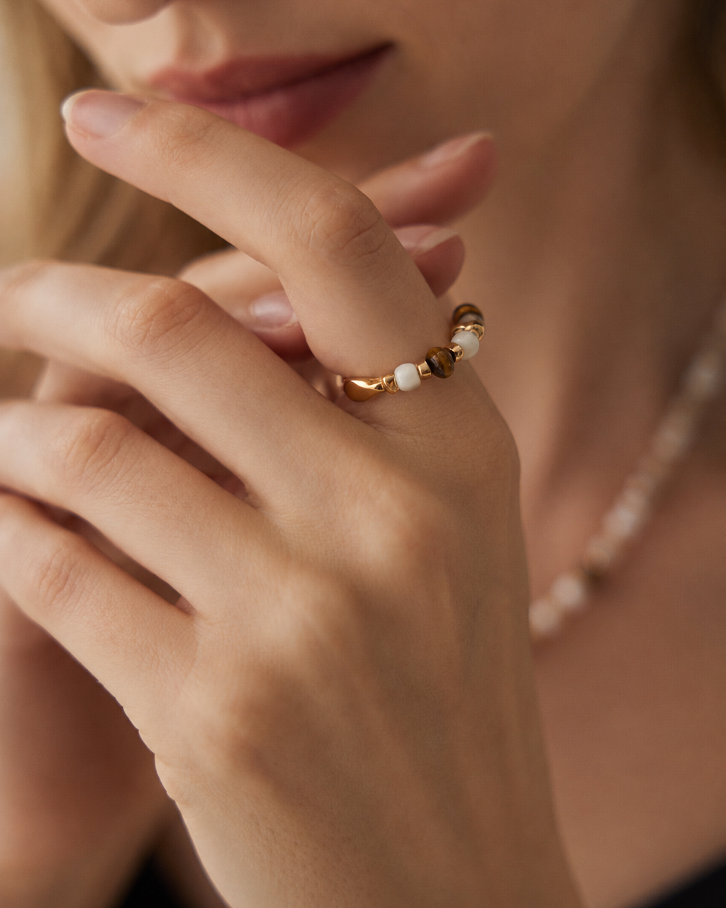 Hand close-up showcasing a Tiger Eye and Mother of Pearl beaded ring made from thick 18K gold plated S925 sterling silver.