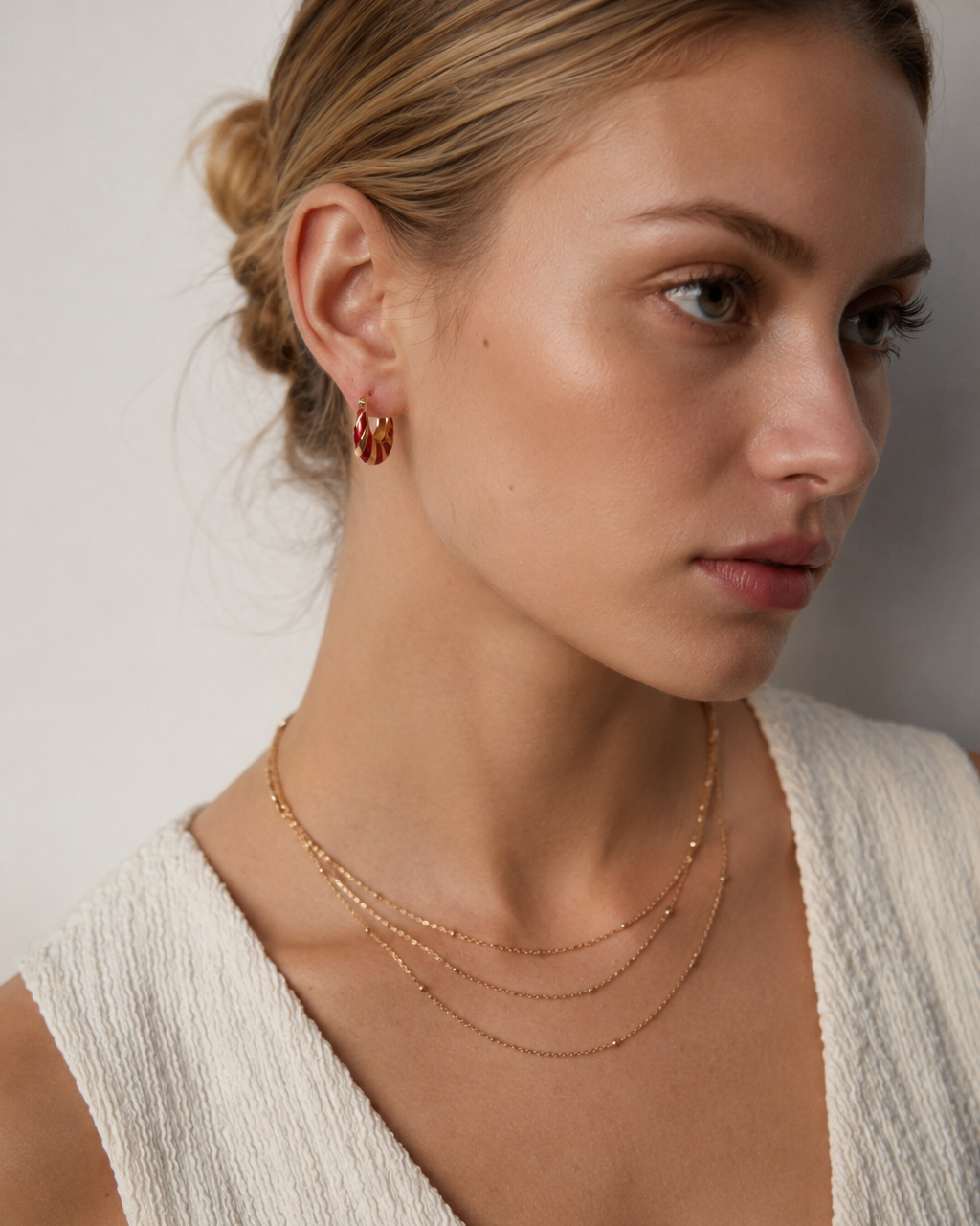 Model wearing red enamel and 18K gold plated hoop earrings, featuring a bold striped design with a sophisticated vintage aesthetic.