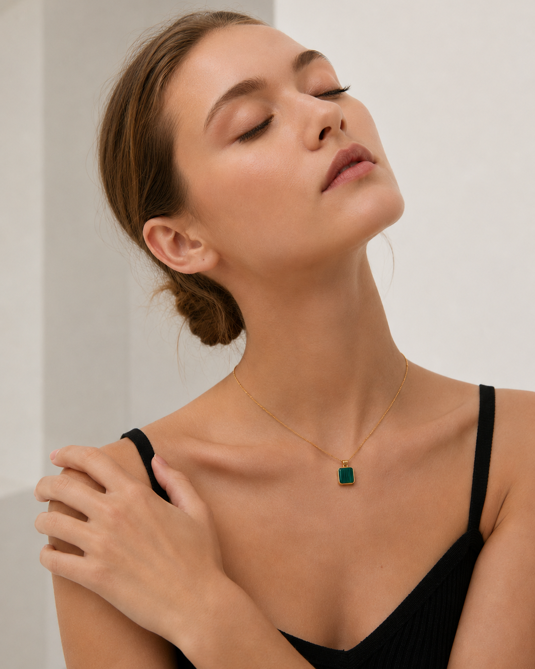 Female model wearing a square natural malachite pendant necklace in thick 18K gold plated sterling silver, styled with a minimalist black dress.