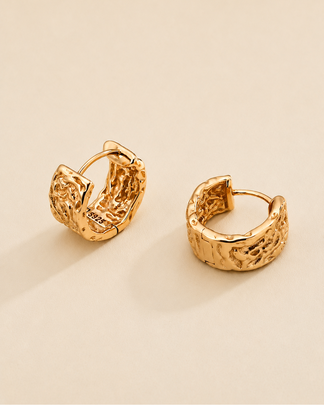 Close-up of vintage carved huggie hoop earrings in thick 18K  gold plated S925 sterling silver on a soft ivory background.